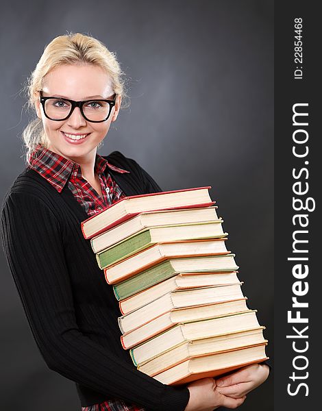 Inteligent woman in glasses with books.Black background.