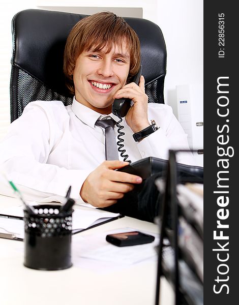 Young and successful businessman talking by phone in his office