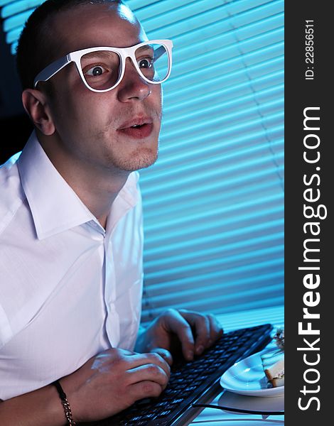 Funny nerd in glasses surfs internet at night time. Funny nerd in glasses surfs internet at night time