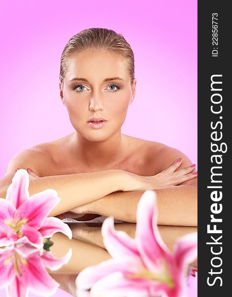 Young and beautiful woman with lily flower over pink background