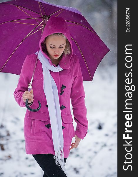 Portrait of pretty young girl in jacket with hood walking under an umbrella in winter park. Portrait of pretty young girl in jacket with hood walking under an umbrella in winter park