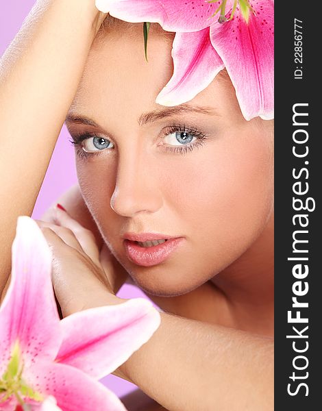 Young and beautiful woman with lily flower over pink background