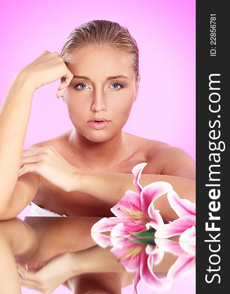 Young and beautiful woman with lily flower over pink background