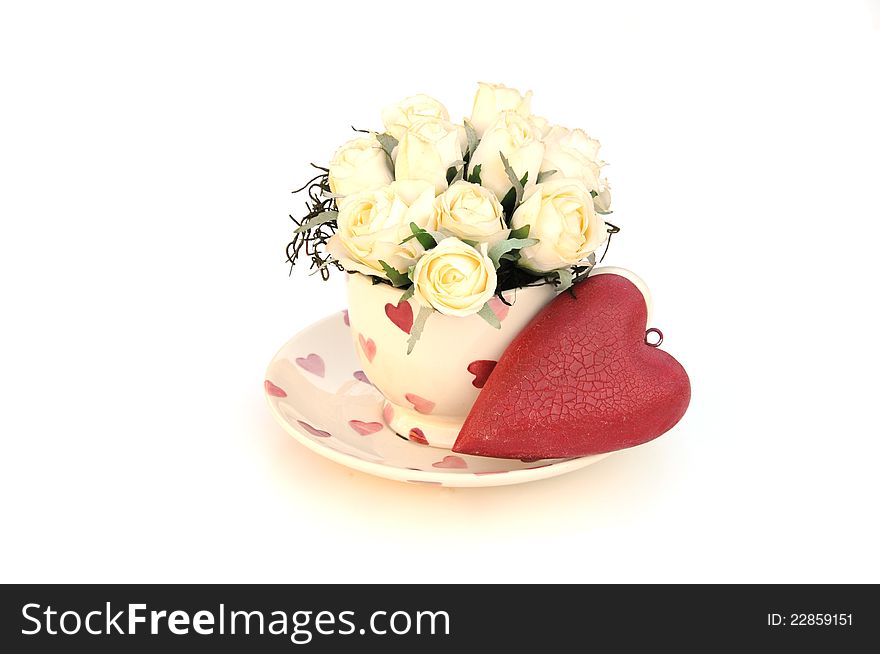 Pretty cream roses in a teacup and a red vintage love heart. Pretty cream roses in a teacup and a red vintage love heart