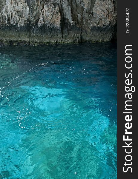 Blue coastal sea with small vawes. Rocky coast as acontrast in background. Blue coastal sea with small vawes. Rocky coast as acontrast in background