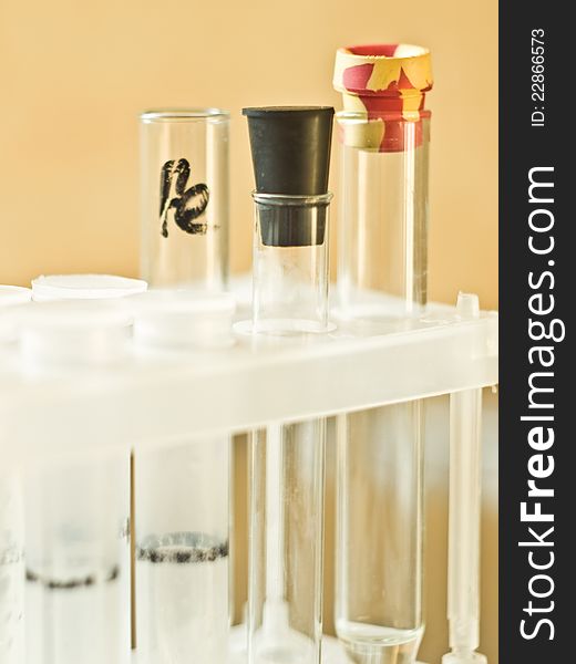 Glass and plastic vials in a plastic tripod stand on a yellow background. Glass and plastic vials in a plastic tripod stand on a yellow background