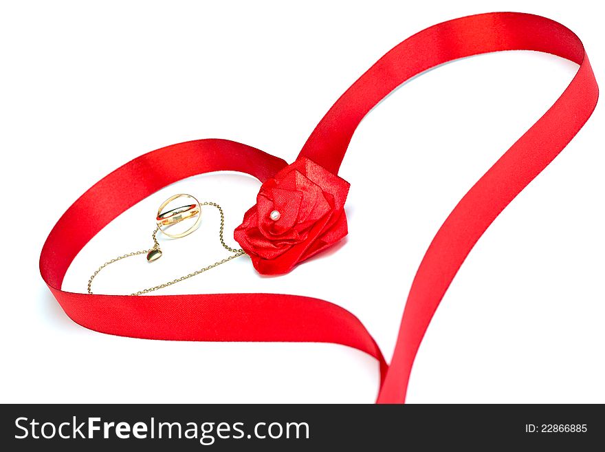 Golden wedding bands and chain with heart surrounded by red ribbon in heart shape with rose bow isolated on white. Golden wedding bands and chain with heart surrounded by red ribbon in heart shape with rose bow isolated on white