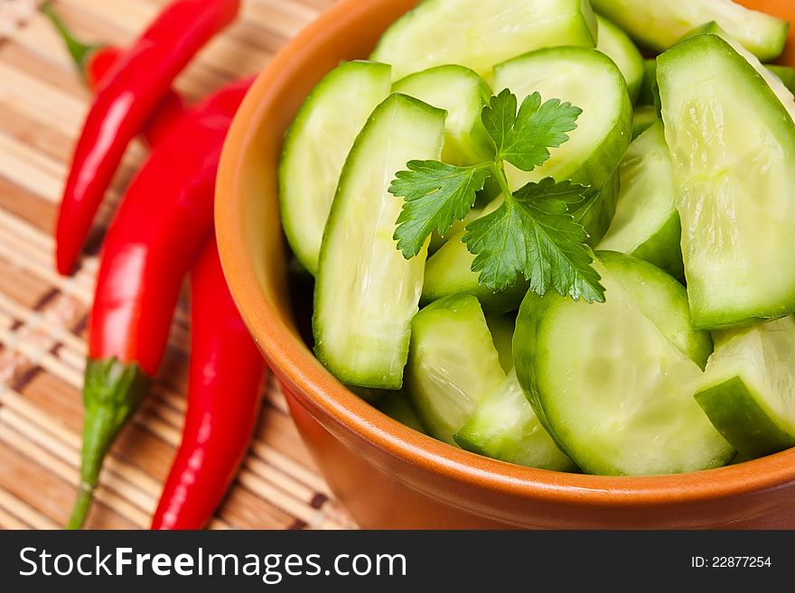 Chopped cucumber in a brown bowl decorated with parsley