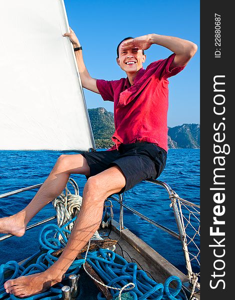 Smiling young man on the yacht looks afar