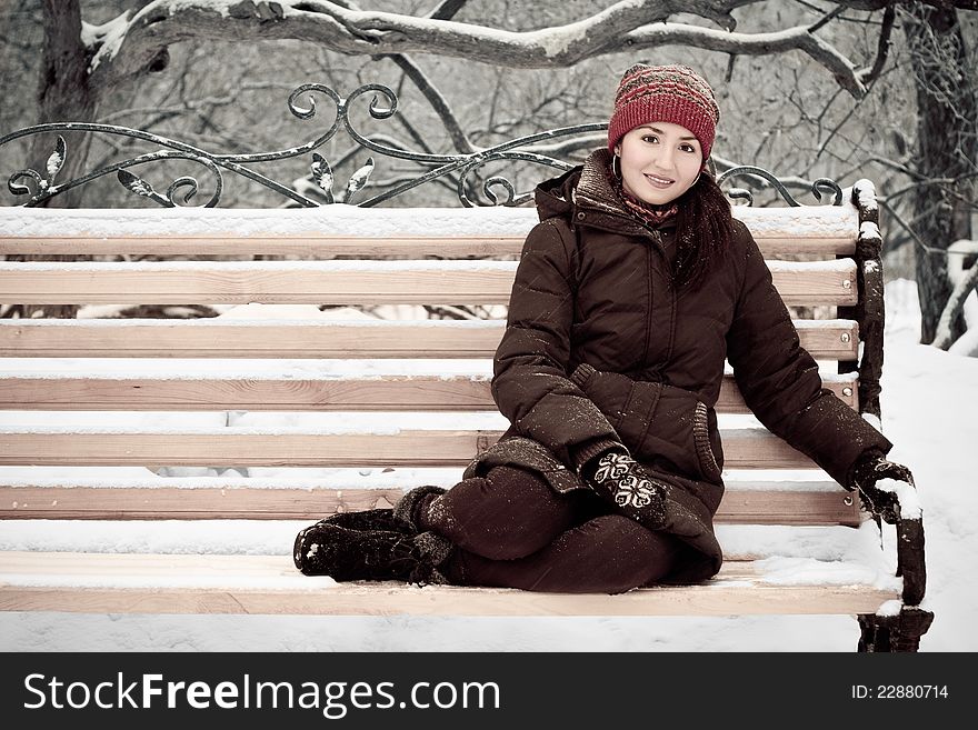 Young woman in winter park on a bench