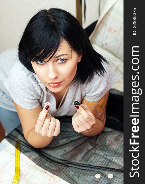 Young seamstress with tattoo choosing buttons on sewing pattern. Young seamstress with tattoo choosing buttons on sewing pattern