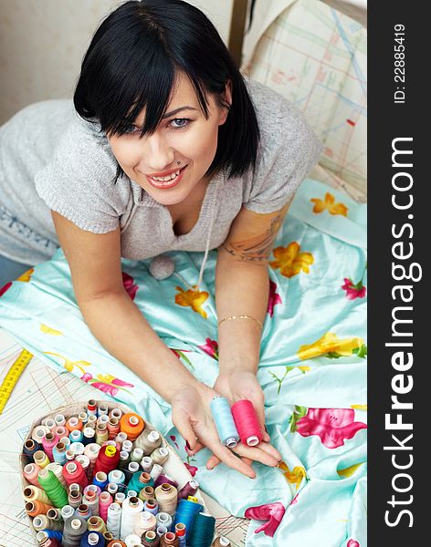 Young seamstress with tattoo choosing thread on sewing pattern. Young seamstress with tattoo choosing thread on sewing pattern