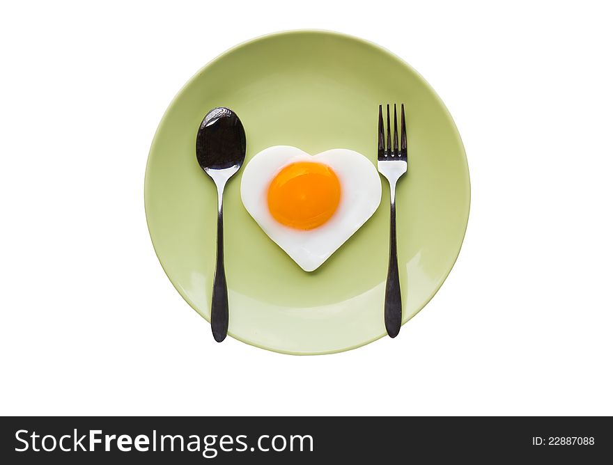 Fried egg heart and spoon on green dish