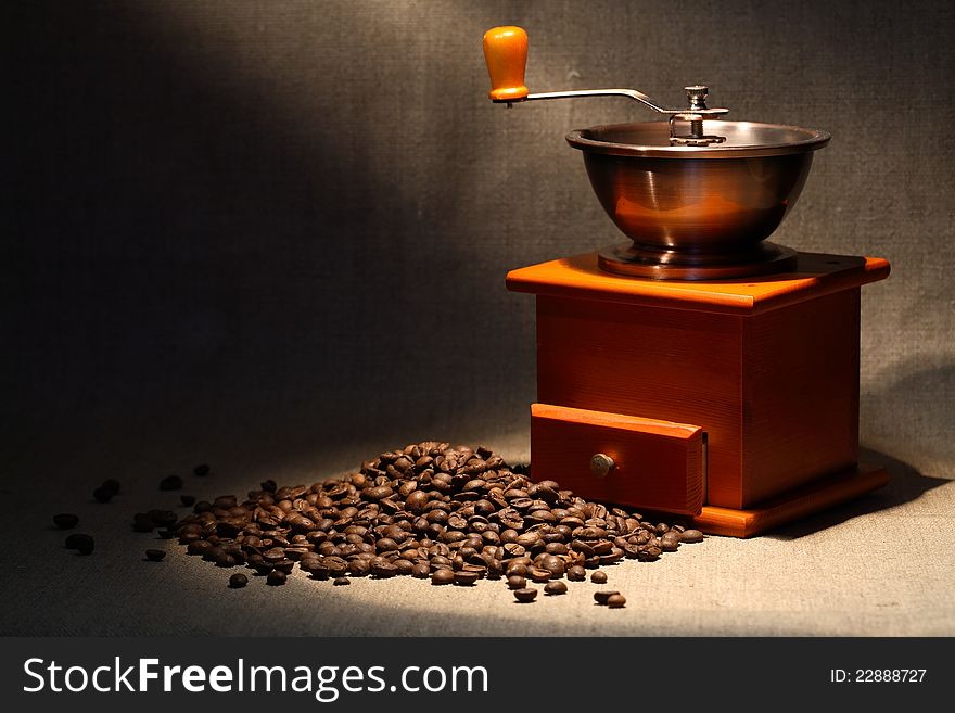 Nice vintage manual coffee grinder near beans on canvas background. Nice vintage manual coffee grinder near beans on canvas background