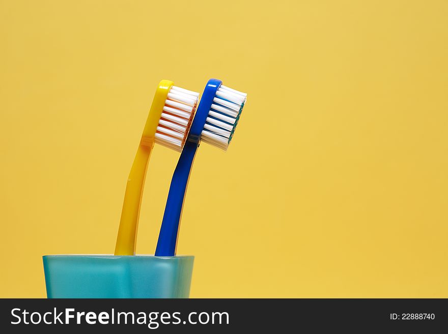 Pair of toothbrushes on yellow background with free space for text