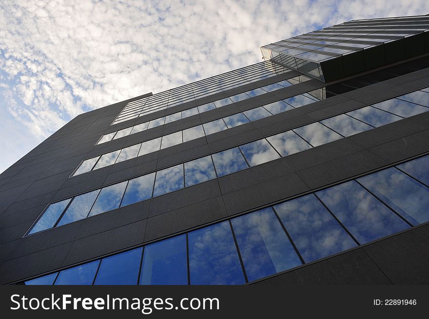 Portrait of modern office building with windows reflecting a cloudy sky. Portrait of modern office building with windows reflecting a cloudy sky