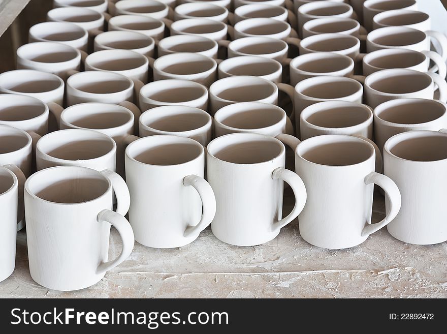 Ceramic mugs in racks in ceramic work shop