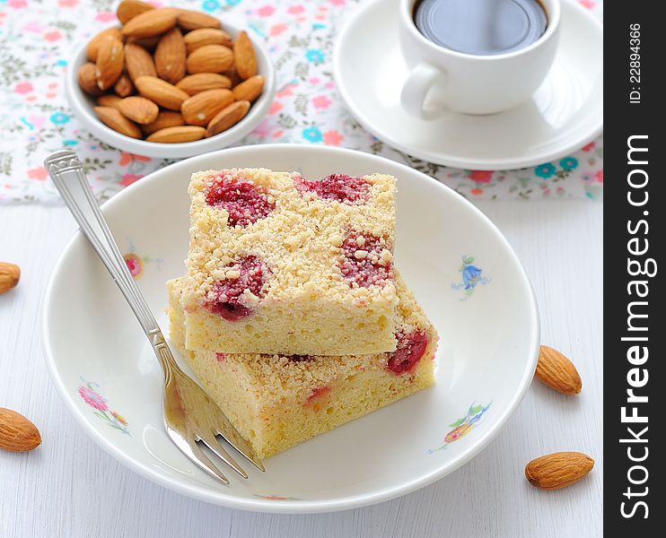 A piece of cake with cherries and almonds on a white plate and white. A piece of cake with cherries and almonds on a white plate and white