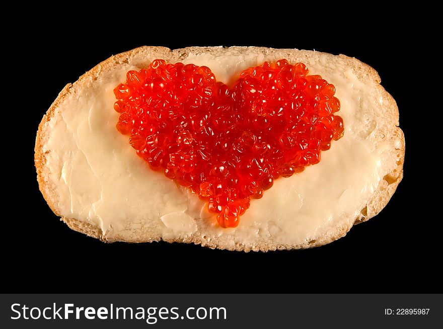 Heart made of red caviar on bred and butter isolated on black. Heart made of red caviar on bred and butter isolated on black