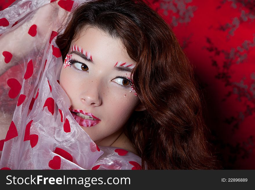 Sexy woman with candy makeup  in a red dress holding heart shaped fabric. Sexy woman with candy makeup  in a red dress holding heart shaped fabric