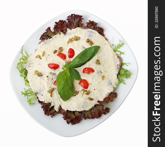 Dairy veal with tuna sauce with tomatoes on a dish isolated on a white background. Top view.