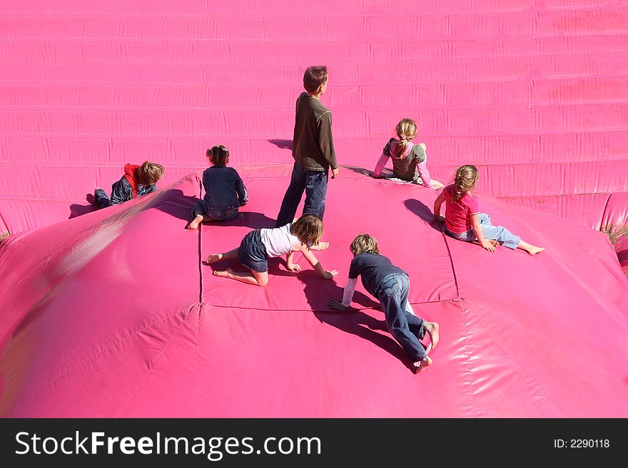 Children playing on a large air-filled cushion on the beach. Children playing on a large air-filled cushion on the beach