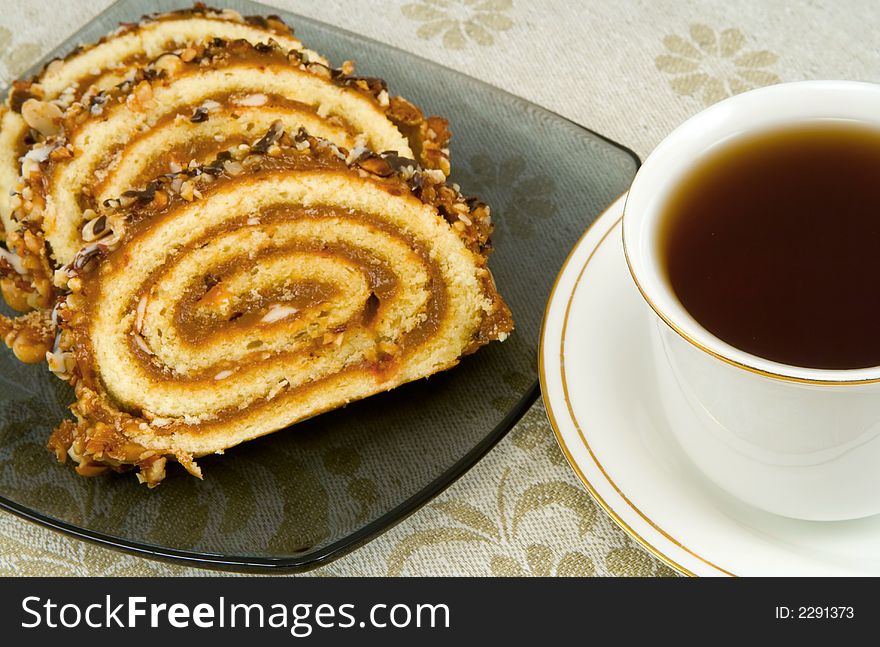 Swiss roll on a plate and cup of tea