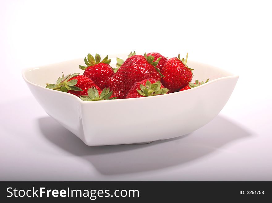 A white bowl with red strawberries on a white background. A white bowl with red strawberries on a white background