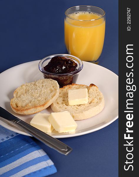 English muffin with butter, grape jam and a glass of orange juice