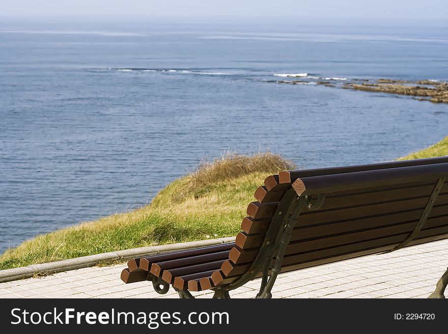 A wooden bench alone in front of the sea in a coast of Cantabria, Spain. A wooden bench alone in front of the sea in a coast of Cantabria, Spain.