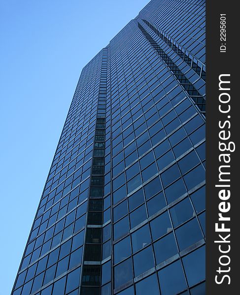 Perspective view of a blue glass-windowed skyscraper.