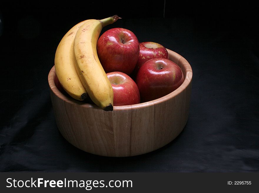 A bowl of healthy apples and bananas in low key lighting. A bowl of healthy apples and bananas in low key lighting.