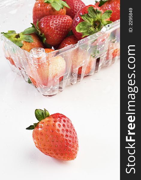 Plastic box of strawberries on white
