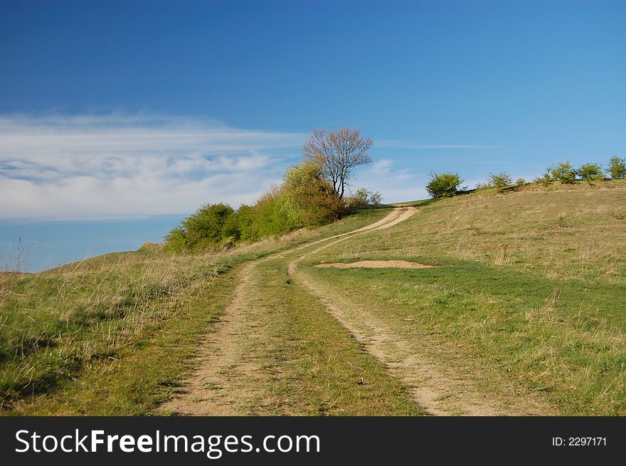 Field with grass and blue sky with clouds, road touchink the sky. Field with grass and blue sky with clouds, road touchink the sky