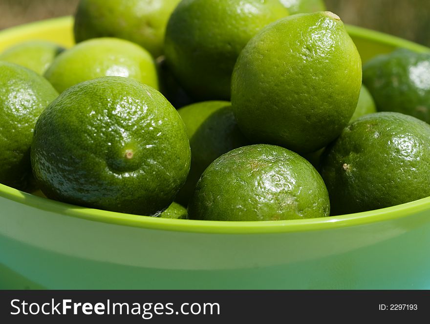 Limes up close in a green bowel in outdoor setting.