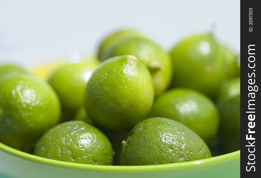 Limes up close in a green bowel in outdoor setting.