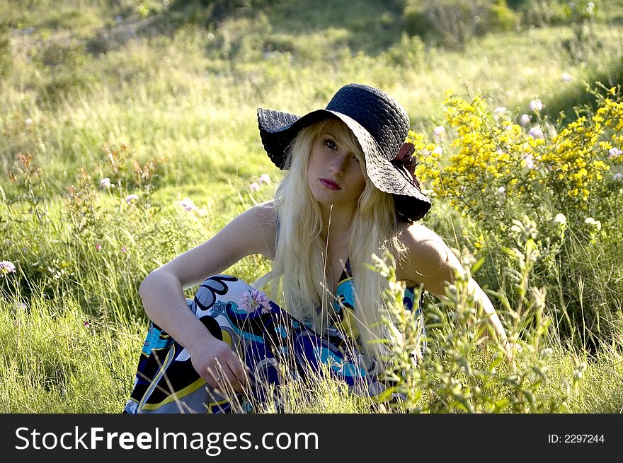 Girl sitting in meadow in sunshine looking forward. Girl sitting in meadow in sunshine looking forward