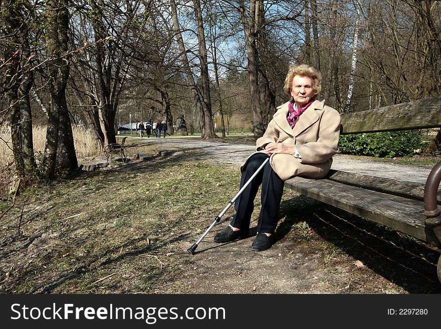 An elderly woman is enjoying the first sunrays in a park!. An elderly woman is enjoying the first sunrays in a park!