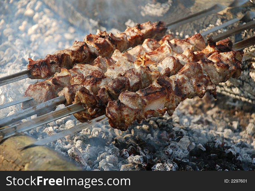 Meat grilled on fire. Barbeque. Metal rods. Meat grilled on fire. Barbeque. Metal rods.