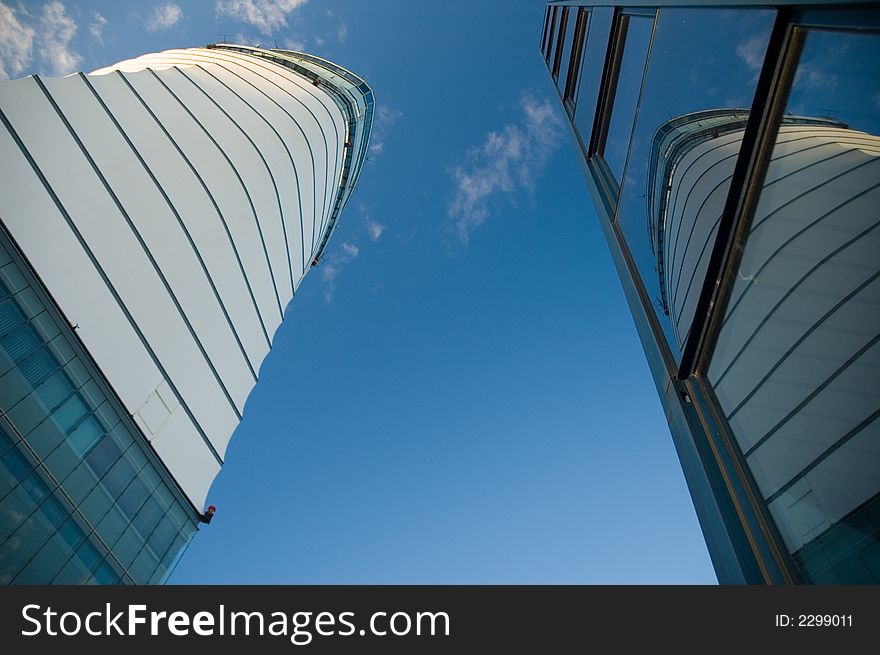 Business skyscrapers with windows fully made of glass mirroring sky and clouds, other skyscrapers and buildings. Business skyscrapers with windows fully made of glass mirroring sky and clouds, other skyscrapers and buildings.