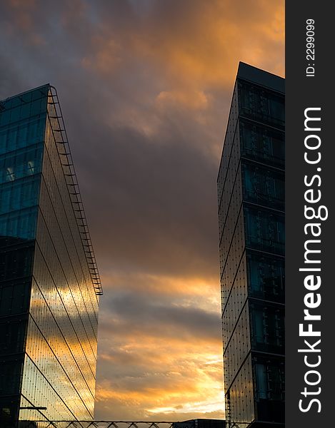 Business skyscrapers with windows fully made of glass mirroring sky and clouds, other skyscrapers and buildings.