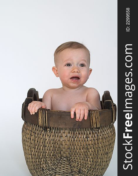 Image of cute baby sitting in a woven basket. Image of cute baby sitting in a woven basket