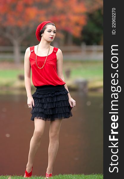 A portrait of a pretty young woman in a fashionable outfit, standing by a lake in the fall. A portrait of a pretty young woman in a fashionable outfit, standing by a lake in the fall