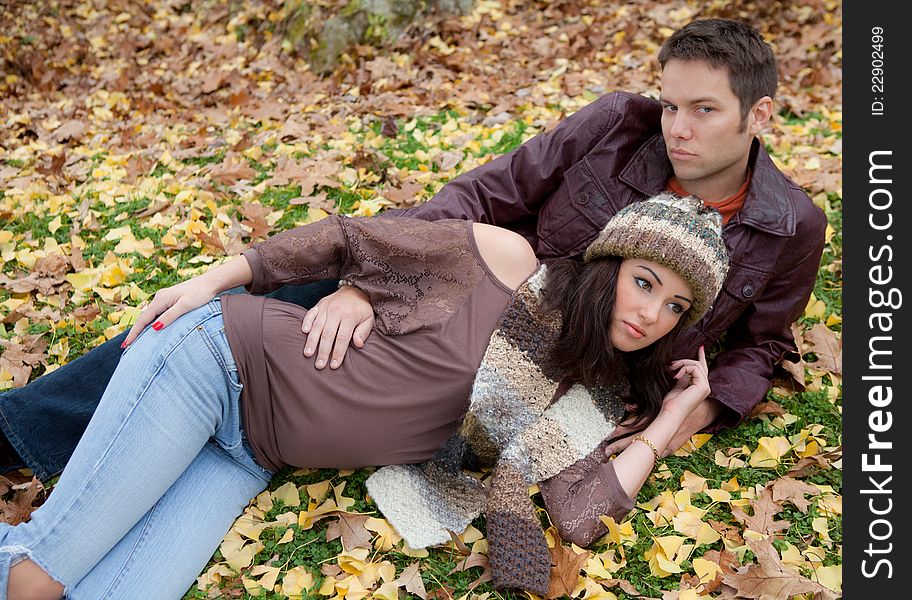 A portrait of an attractive couple, lying together in the grass in the fall or winter. A portrait of an attractive couple, lying together in the grass in the fall or winter