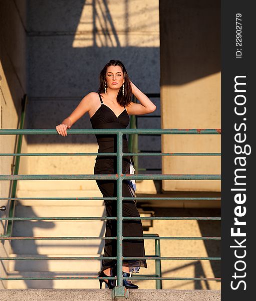 A portrait of a beautiful, elegantly dressed woman outdoors on set of stairs on a downtown parking garage. A portrait of a beautiful, elegantly dressed woman outdoors on set of stairs on a downtown parking garage