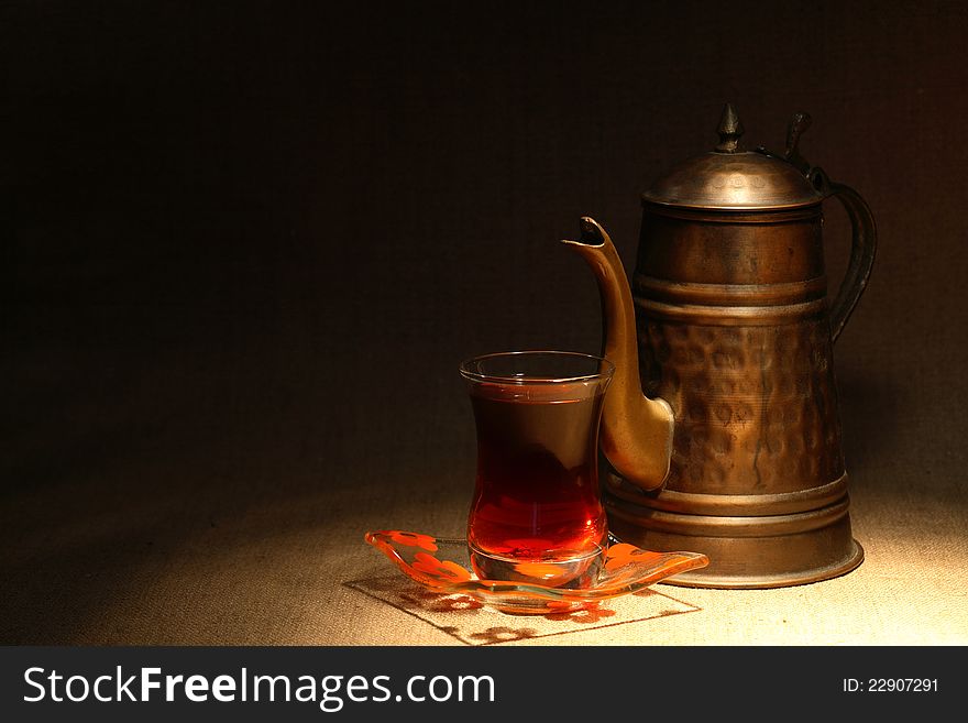 Still life with oriental tea cup near copper teapot on canvas surface. Still life with oriental tea cup near copper teapot on canvas surface
