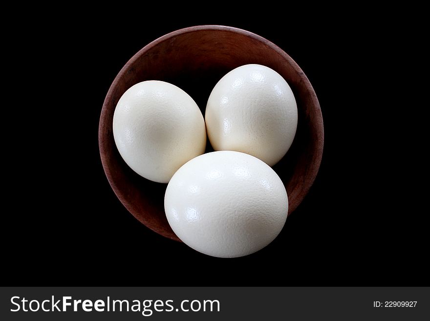 Three ostrich eggs in a wooden bowl