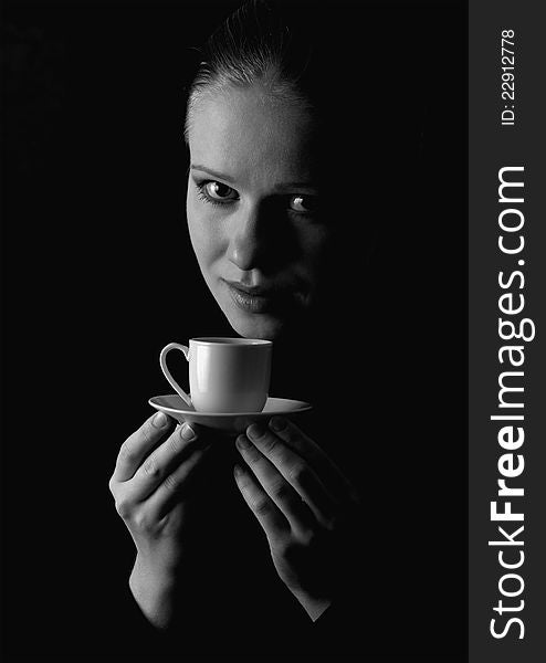 Monochrome portrait of a beautiful girl with a cup of coffee on a black background. Monochrome portrait of a beautiful girl with a cup of coffee on a black background