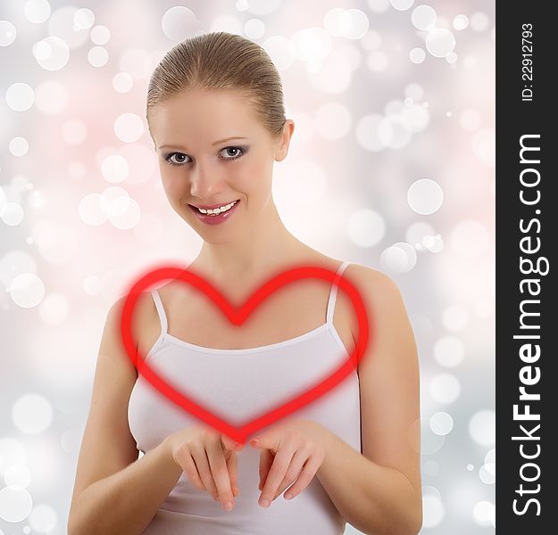 Beautiful young woman draws a big red heart on an abstract background