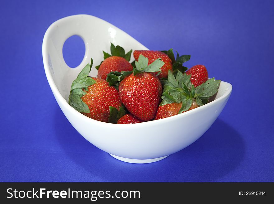 Fresh and juicy strawberries in a white bowl on purple bacground. Fresh and juicy strawberries in a white bowl on purple bacground.
